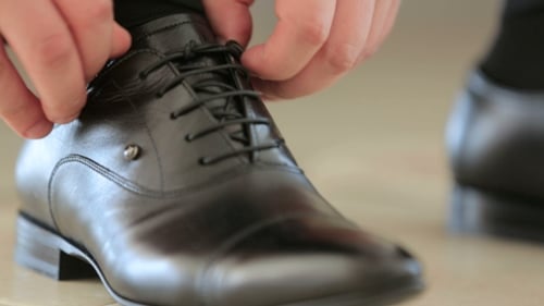 Man Tying the Laces of a Black Leather Shoe