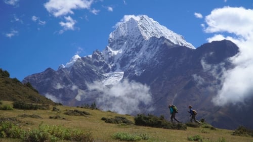 Girls with Backpacks Climb the Mountain Slope in the Himalayas