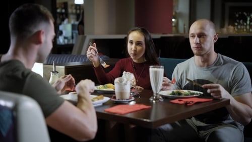 Cheerful Young Couple Is Dining in a Cafe with Their Friend, They Are Talking and Smiling