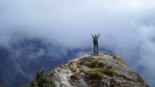 Girl with Backpack Reaching Up Top of Mountain and Raised Hands