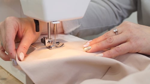 Footage of a Woman Sewing a Pink Cotton with a Sewing Machine.