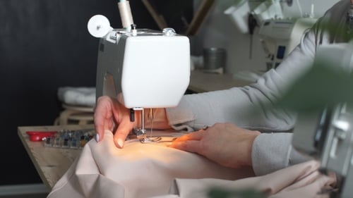 Woman Sews Light Pink Fabric on Machine