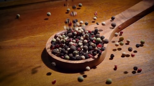 Colorful Peppercorns Falling into Wooden Spoon Close Up