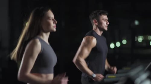 Wellness Female and Man Athlete Run on a Treadmill Two Runners Perform Aerobic Exercise