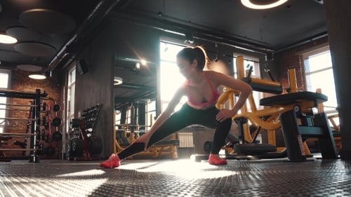 Fitness Girl Doing Warm-up in the Gym. Stretching and Preparation for Training