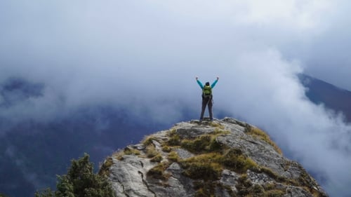 Girl with Backpack Reaching Up Top of Mountain and Raised Hands