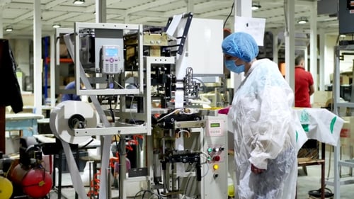 Worker Operates Automated Manufacturing and Packaging Machine