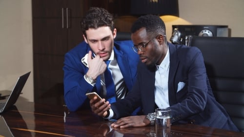 Two Men Collaborating on Smartphone at Office