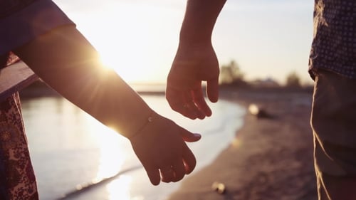 Two Lovers Joining Hands near the Sunset Lake