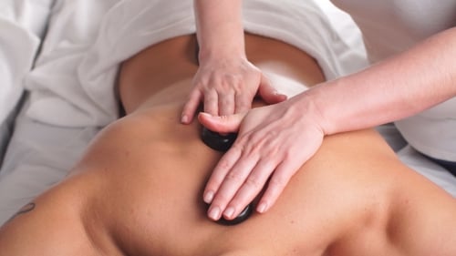 Mann entspannt sich im Spa-Salon mit heißen Steinen am Körper. Therapie der Schönheitsbehandlung.