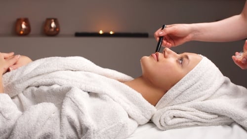 Cosmetician Applying Facial Mask To the Face of Young Woman in Spa Salon.