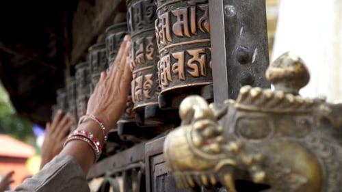 Hands Spinning Prayer Wheels with Embossed Writing