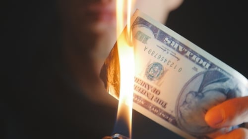 Man Burns a Dollar Bill in a Dark Background