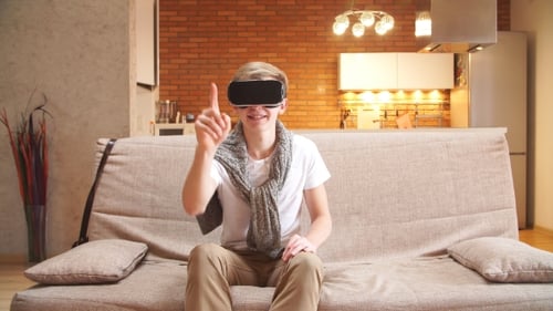 Junger Mann benutzt Virtual-Reality-Brillen im Haus und blättert durch die virtuellen Seiten.