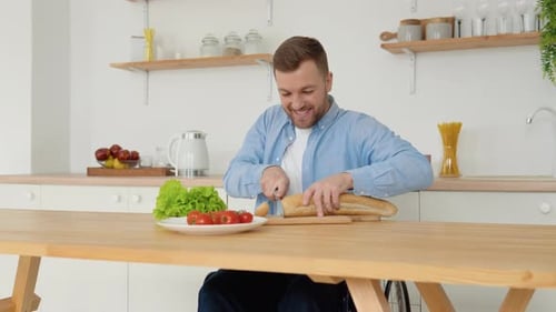 Man in Wheelchair Cuts Bread at Kitchen Table