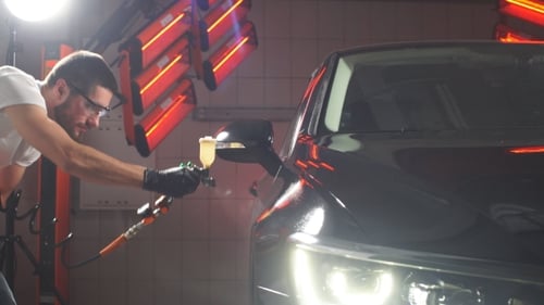 Man Detailing Black Car in Auto Body Shop