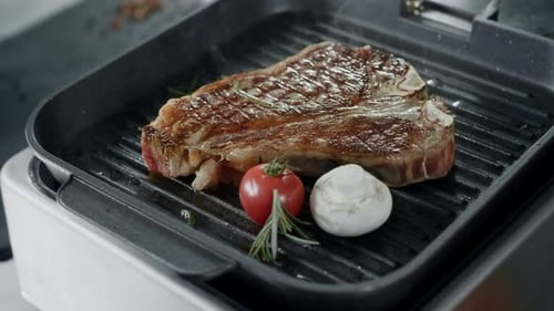Fresh Steak Frying at Griddle Pan. Closeup Beef with Vegetables Cooking at Grill