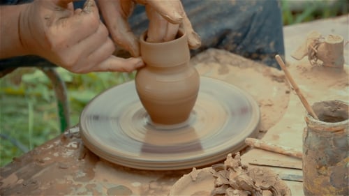 Mains façonnant un pot en argile sur un tour de poterie.