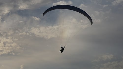 Tandem Paragliding High in Cloudy Sky
