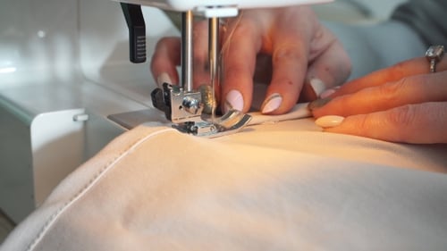 Senior Seamstress Is Working on a Sewing Machine at a Clothing Manufactory.