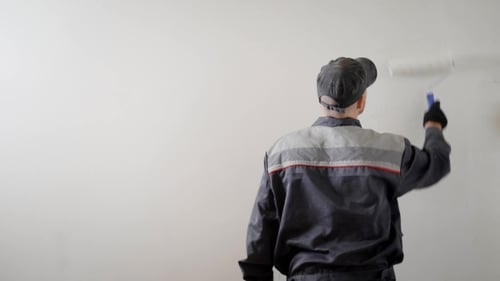 Man Painting White Wall with Paint Roller