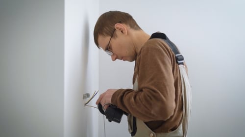 Electrician Is Connecting Wires To Wall Lamp for Installing on a New Walls in a Refurbished