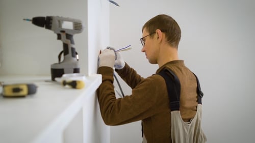 Electrician Is Cutting Wires and Trying on a Mechanism Recessed Socket in a White Wall