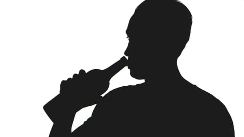 Silueta de un joven bebe alcohol de una botella aislada sobre fondo blanco