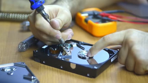 Computertechniker repariert Festplatte am Schreibtisch mit Werkzeugen und Elektronisch Komponenten