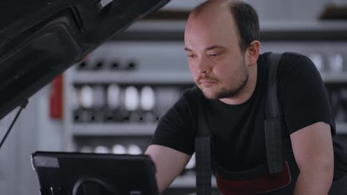Auto Mechanic Working with Car Diagnostic Tool in a Repair Shop