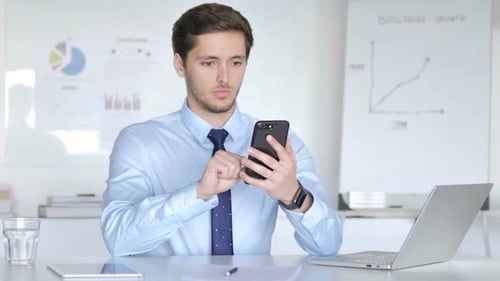 Young Adult Using Smartphone in Bright Office