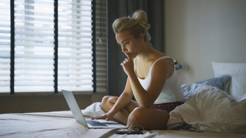 Woman Using Laptop on Bed and Thinking