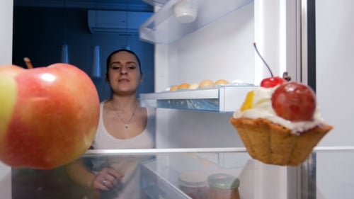 Woman Choosing Apple over Pastry from Refrigerator