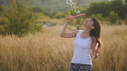 Woman blowing bubbles in sunny field