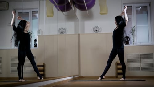 Dancer Woman Is Stretching Arms and Legs Standing in Training Hall in Front of a Huge Mirror Wall