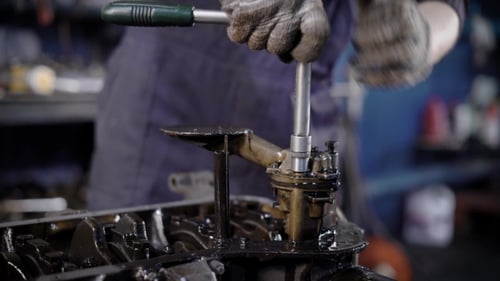 Technicien méconnaissable utilisant une clé lors de la réparation du moteur en atelier