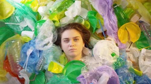 Woman Surrounded by Colorful Discarded Plastic Waste