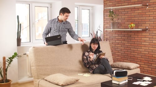 Couple using electronic devices in living room
