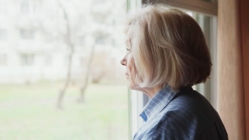 Sad Elderly Woman Looking Out the Window