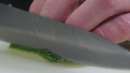 Professional Cook in the Kitchen Cuts a Cucumber