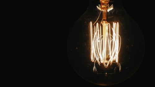 Slowly Lit Electric Bulb Using a Dimmer. On a Black Background