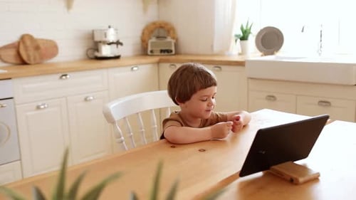 Child Using Tablet Device at Kitchen Table