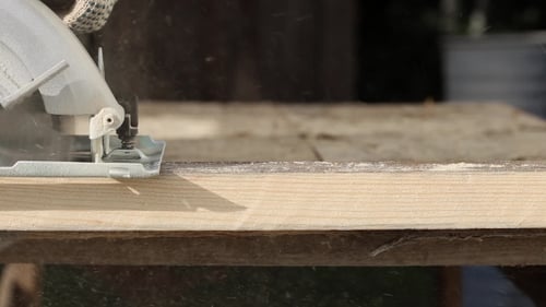 Worker in Gloves Cutting a Wooden Plank with Hand Circular Saw