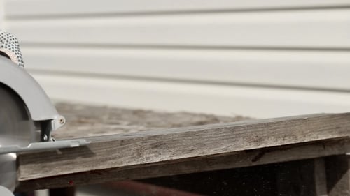 Worker in Gloves Cutting a Wooden Plank with Hand Circular Saw