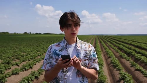Nahaufnahme Junger Mann steht auf der grünen Wiese Handy benutzen Landwirtschaft Industrie Beruf Ernährung Bio
