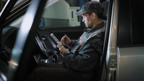 Der Handwerker, der eine Arbeitsuniform trägt, sitzt im Fahrzeug und überprüft das Getriebe