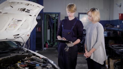 Professional Mechanic Takes the Signature From the Visitor of the Car-care Center for Repairing