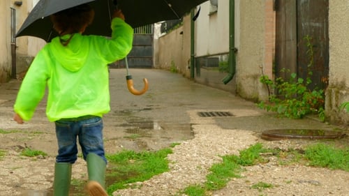 Child Runs with Umbrella Through Rainy Urban Alleyway