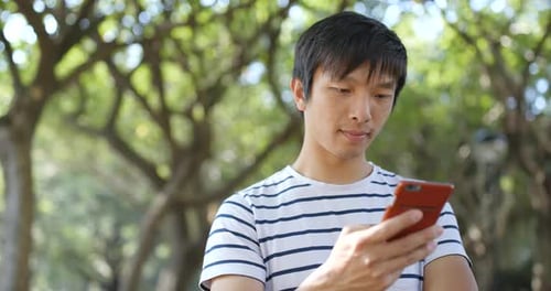 Young Adult Using Smartphone in Urban Green Park