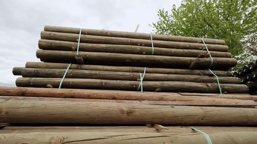 Stacked Lumber Bundles Outside Under Overcast Sky